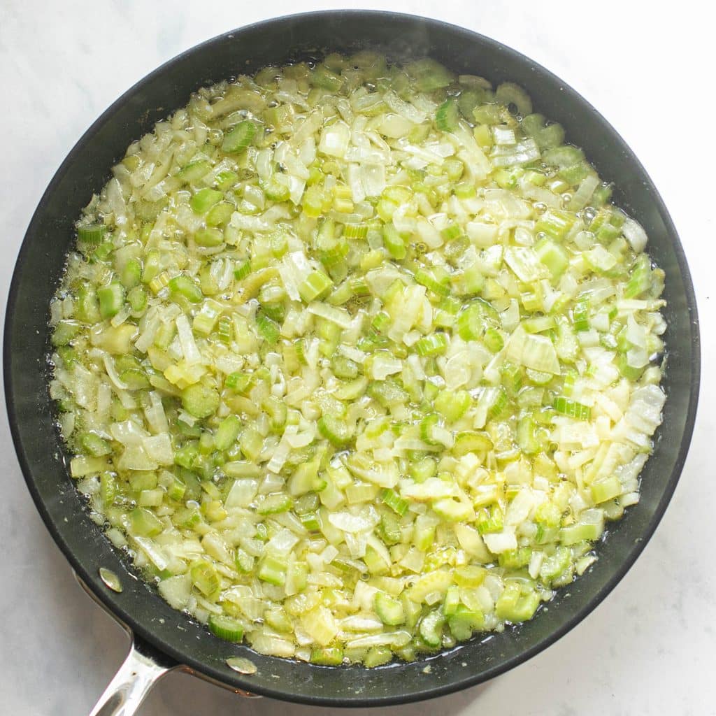 diced onions and celery cooking in a pan