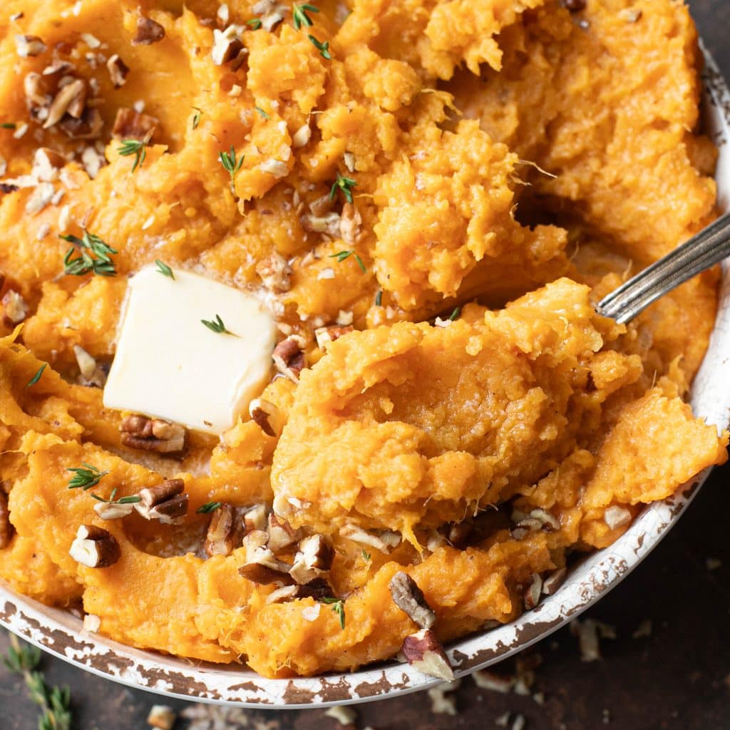 a serving spoon in a bowl of mashed sweet potatoes