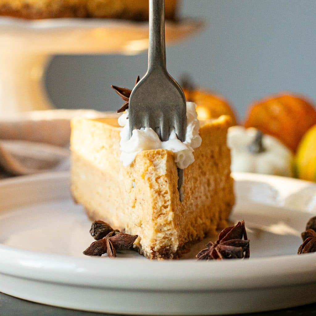 a fork cutting into a slice of pumpkin cheesecake