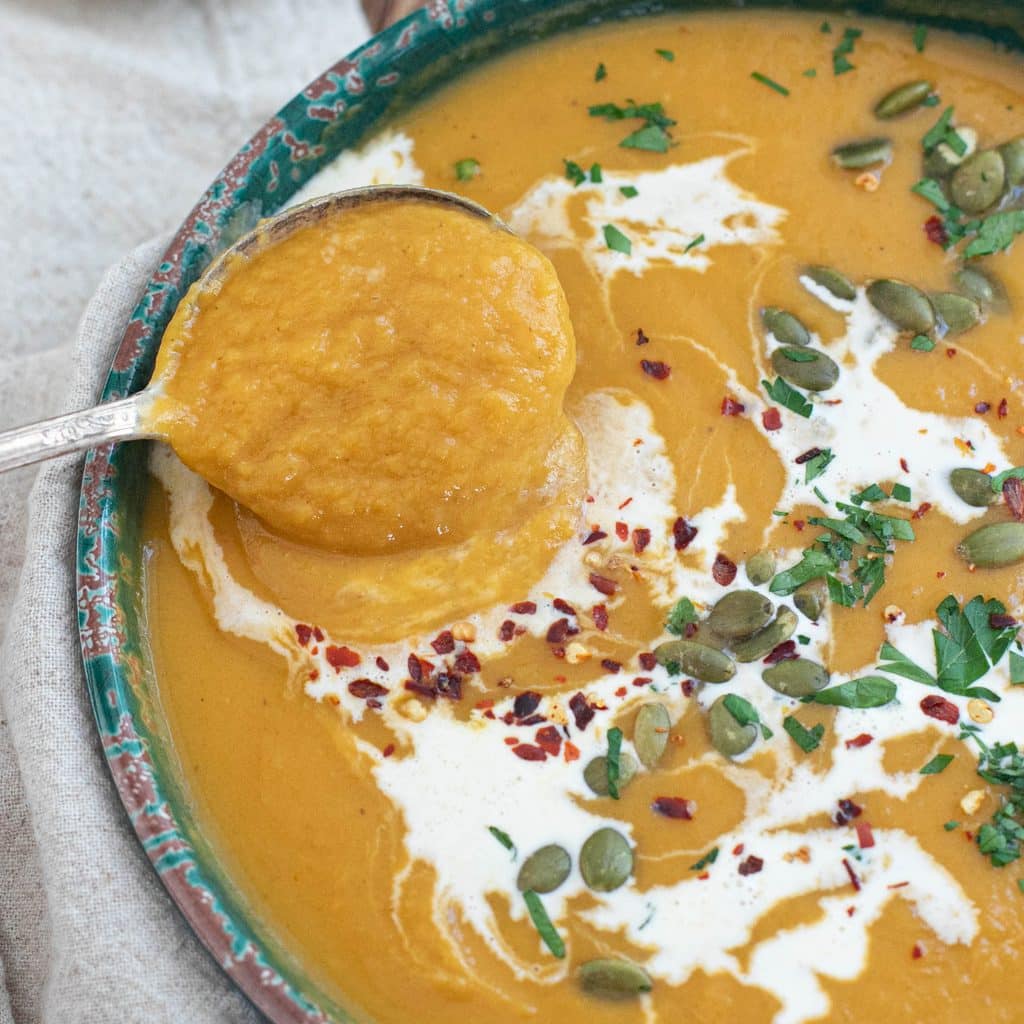 a spoon dipping into a bowl of sweet potato soup