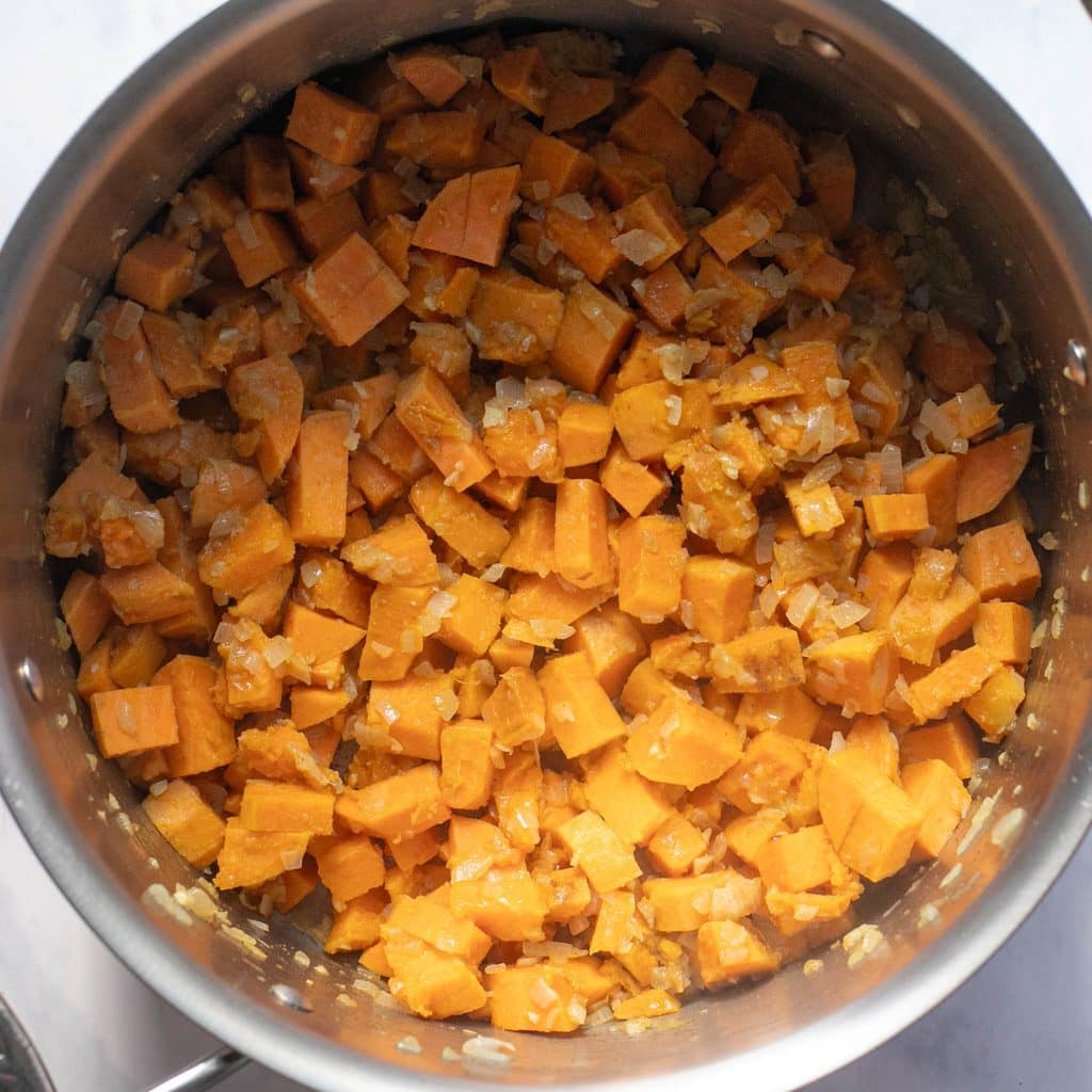 chopped sweet potatoes sweating in a stock pot